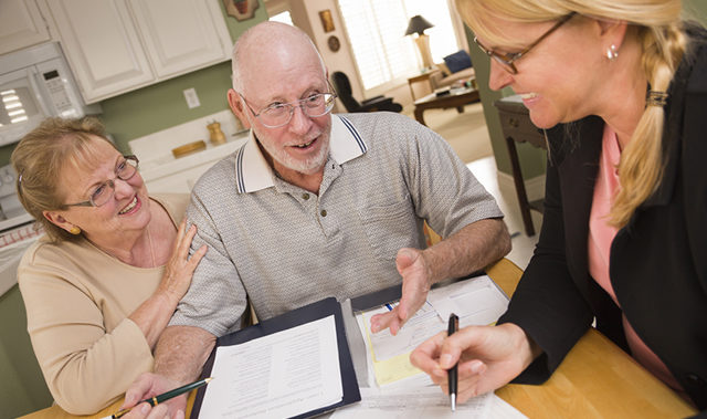 Senior Adult Couple Going Over Papers in Their Home with Agent.